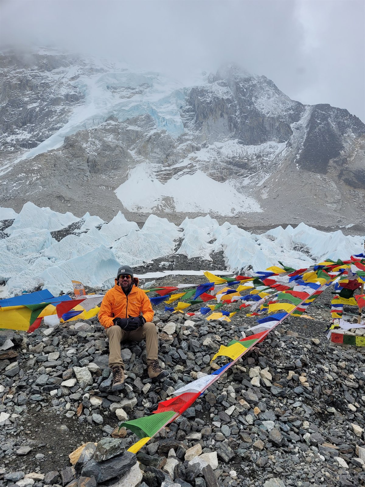 Roger Dudziak seated among prayer flags beneath a snow-covered mountain
